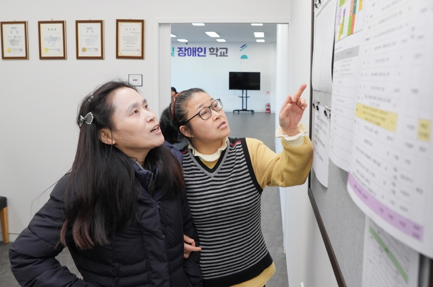 새벽빛 장애인학교 학생들이 새학기 수강신청을 위해 게시판을 보고 상의하고 있다.