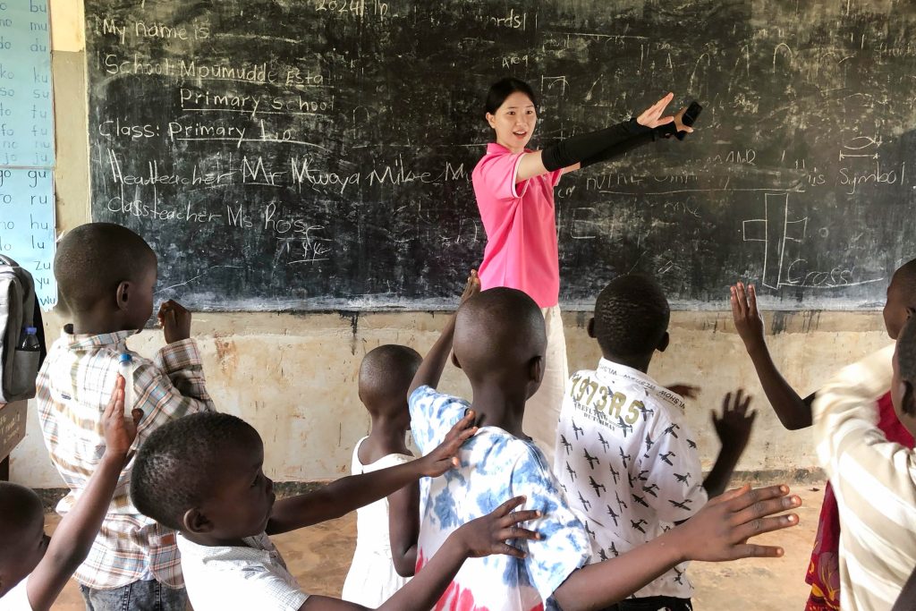 우간다 강민희 단원이 학생들에게 율동을 가르치고 있다. Ⓒ IYF